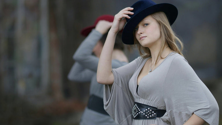 Fashionable woman wearing elegant grey dress and stylish black fedora hat
